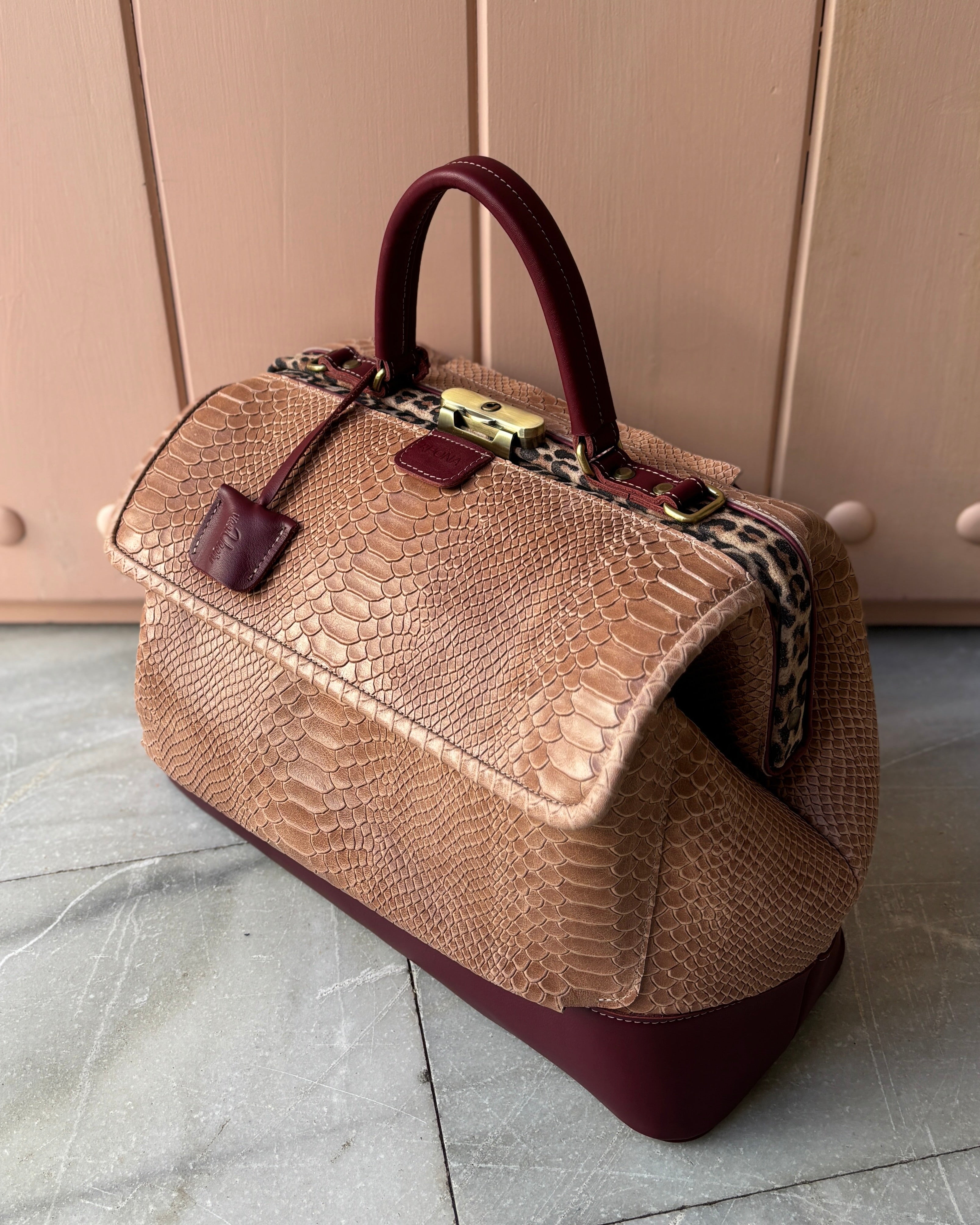 Blush textured handbag with a burgundy matching base on a tiled floor.